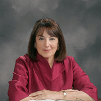 May contain one person sitting at a wooden desk with an open book.