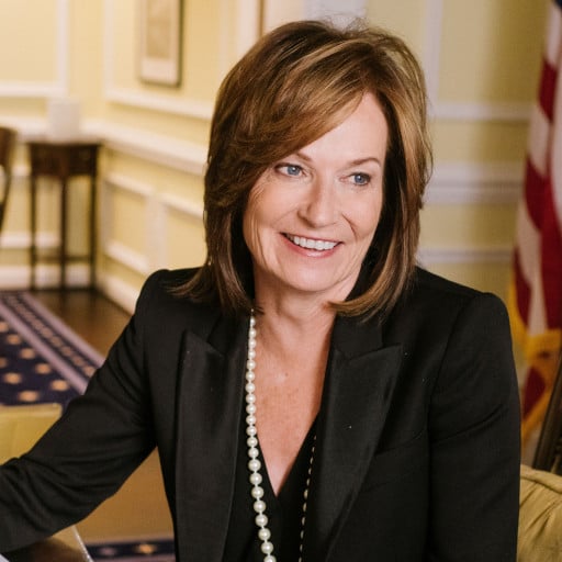 May contain one person wearing a black suit jacket and pearls.