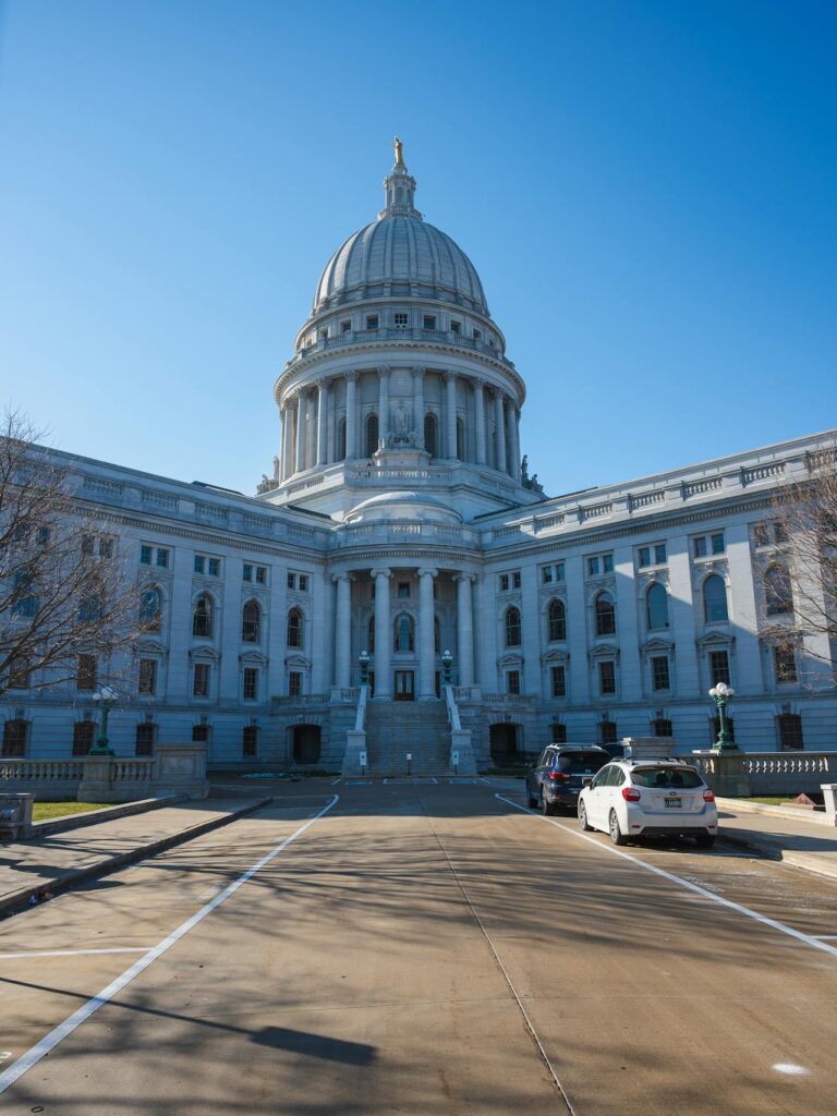 May contain two cars parked near a domed building with columns.