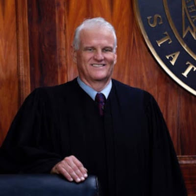 May contain one person in a judge's robe and wig, smiling.