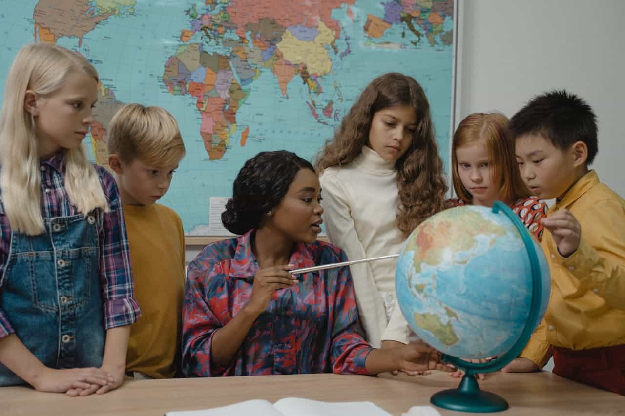 May contain six people looking at a globe.