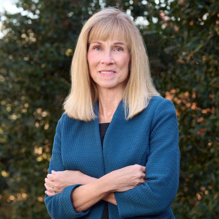 May contain one person smiling, wearing a blue jacket and black dress.