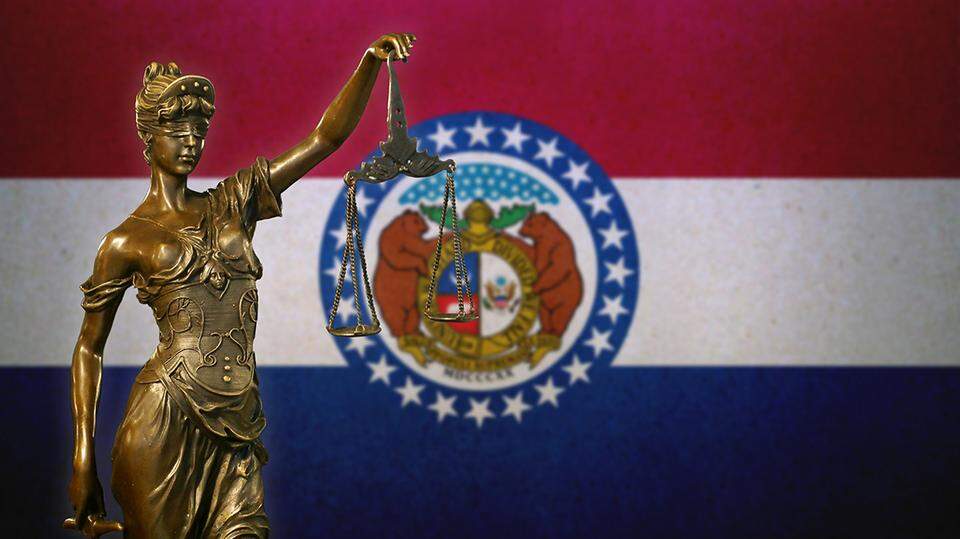 May contain a statue of justice in front of the Missouri flag.