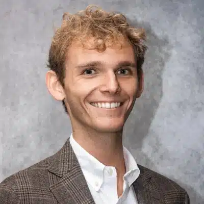 May contain one person smiling, wearing a jacket and white shirt.