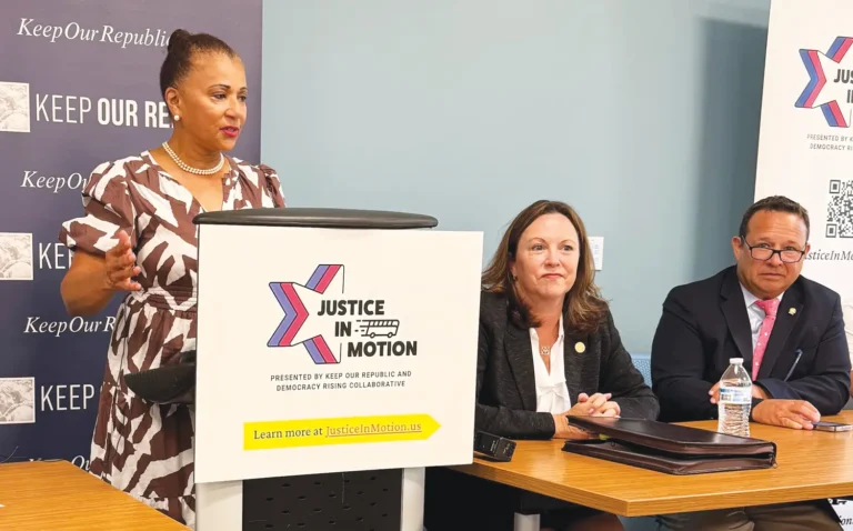 May contain three people at a table with a speaker at a podium.