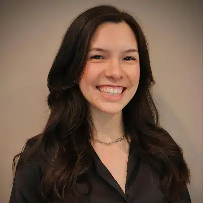 May contain one person smiling, wearing a black shirt and necklace.