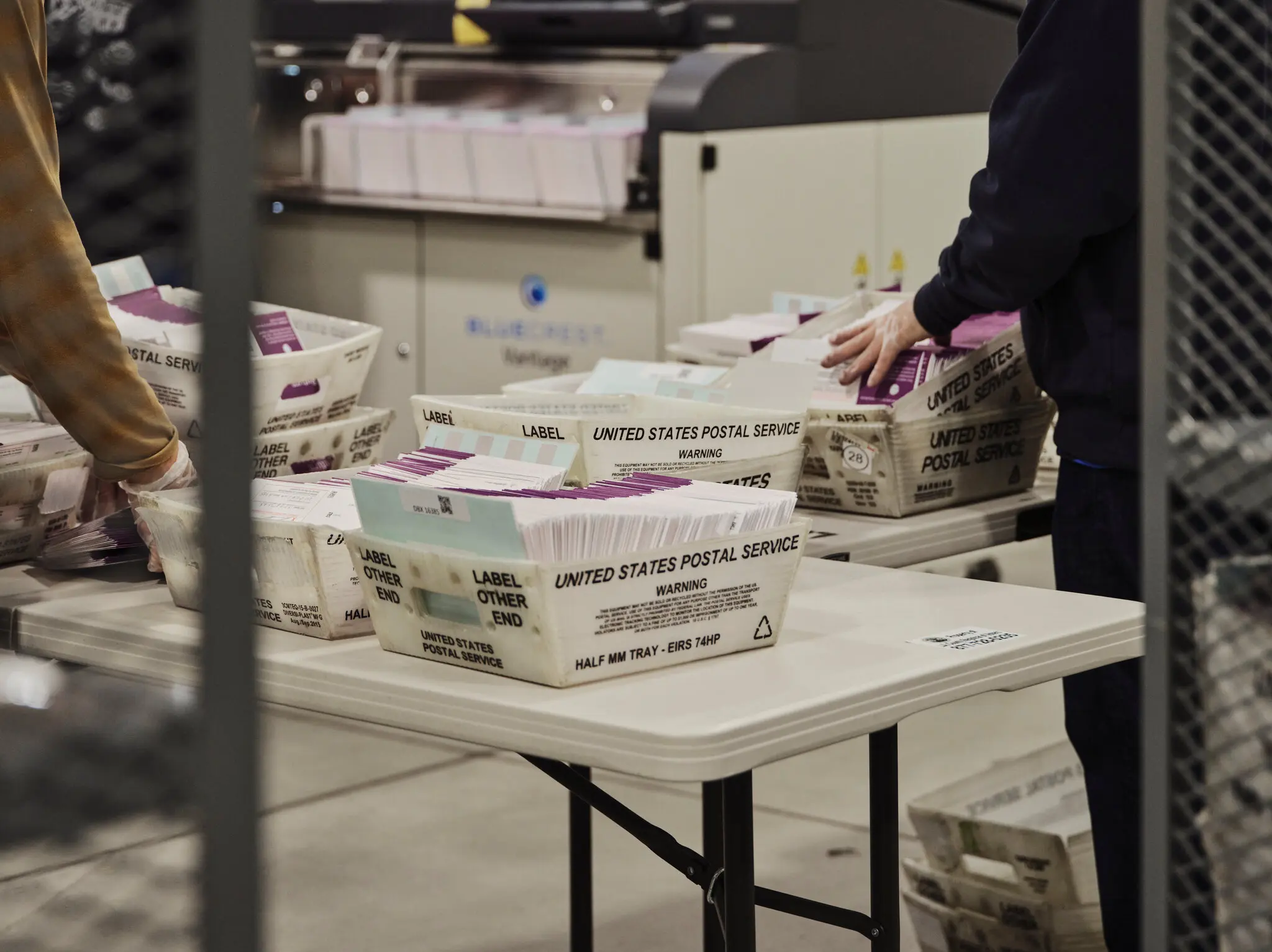 May contain two people handling mail trays.