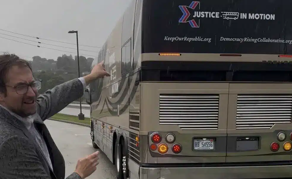 May contain one person pointing at a bus with "Justice in Motion" logo.