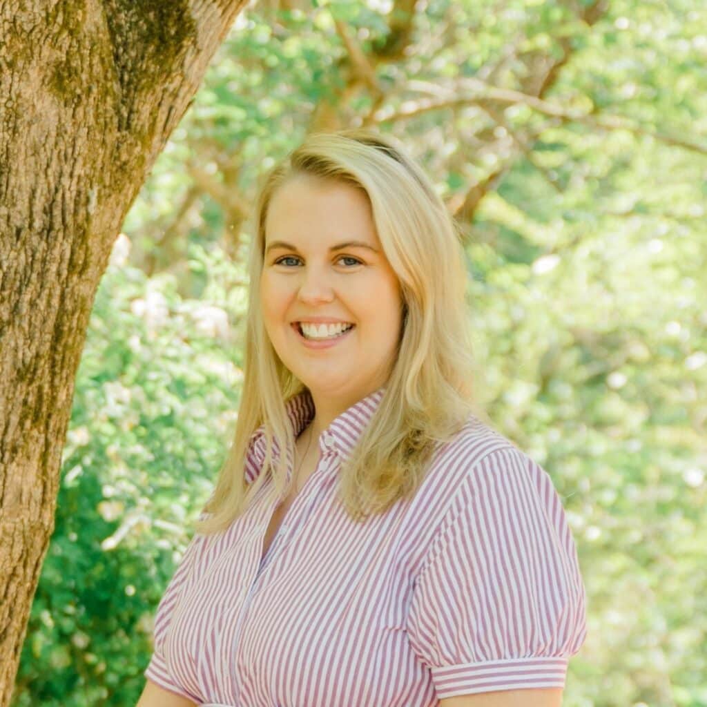 May contain one person smiling next to a tree.