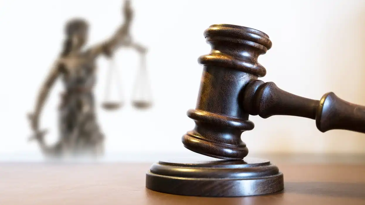 May contain a gavel and a blurred statue of justice with scales.