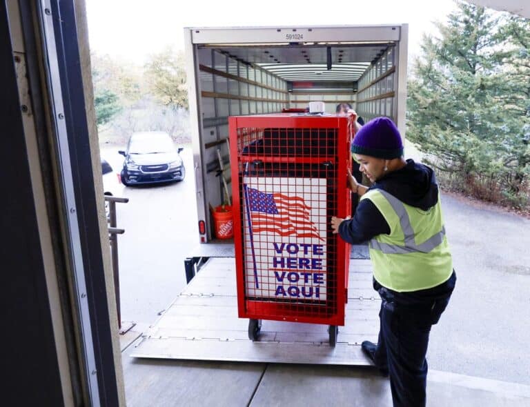 May contain a person in a neon vest loading a voting booth.