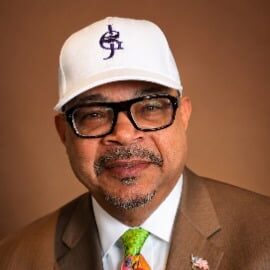 May contain a person wearing glasses, a white baseball cap, and a colorful tie.