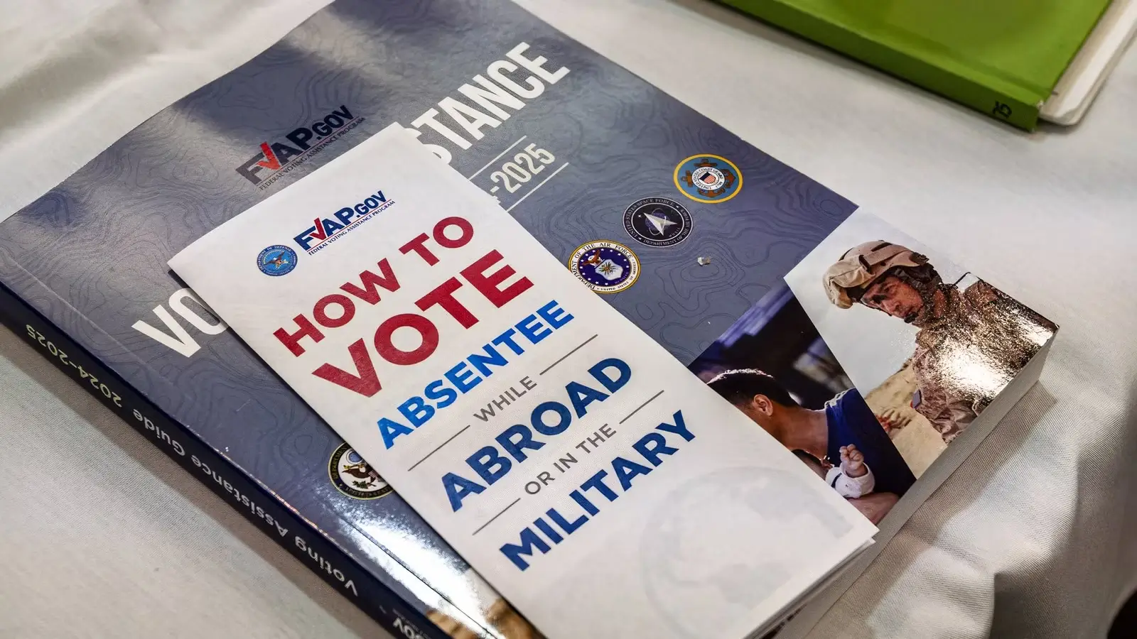 May contain a pamphlet titled "How to Vote Absentee" on a book.